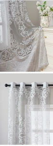 Macro shot of grey voile curtain with white floral embroidery and black metal grommets