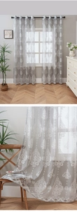 Close-up of gray sheer curtain with white damask embroidery and metal eyelet rings