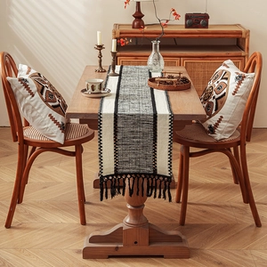 Bohemian woven table runner and matching pillows with black tassels in a cozy dining room