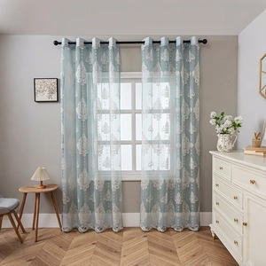 Light blue sheer curtains with white damask embroidery in a bright, modern living room