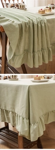 Detail of light green linen tablecloth showing ruffle edge and natural fabric texture