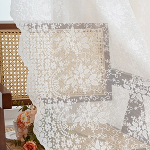 Elegant white lace curtain with floral patterns draped on a chair in French country style