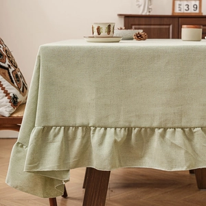 Minimalist light green linen tablecloth with elegant ruffled edges in a rustic cottage style