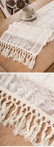 Detail of beige lace table runner featuring retro floral patterns and elegant tassels