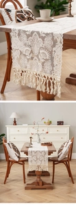 Macro detail of white crochet lace table runner with decorative bohemian tassels