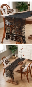 Close-up of black lace table runner featuring butterfly embroidery and tassel fringe details