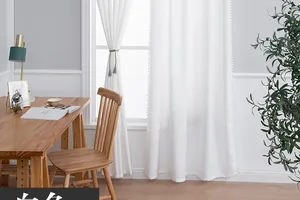 Close-up of white sheer curtain with elegant pom-pom trim for a minimalist interior design