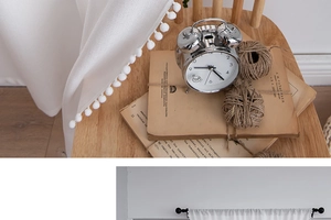 Detailed view of white curtains featuring soft decorative pom-pom trim for home decor