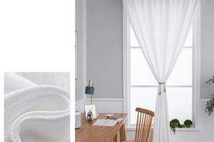 Detail of white semi-sheer curtain fabric with pom-pom edges and tassel tieback