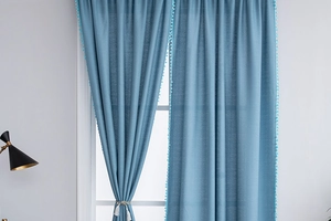 Detail of light blue pom-pom fringe and beige tassel tieback on cotton-linen curtain