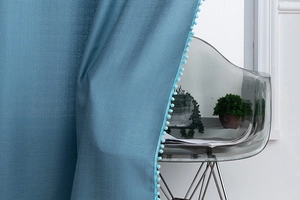 Close-up of blue curtains with pom-pom trim detail and textured flat-weave fabric