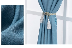 Blue textured linen curtain detail with decorative tassel tieback and pom-pom fringe edges