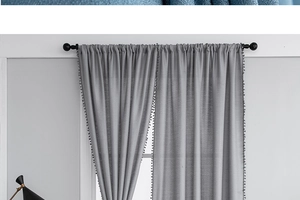 Detail of light gray curtain with elegant pom-pom trim hanging on a black rod