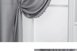 Detailed close-up of grey blackout curtain featuring elegant decorative pom-pom fringe