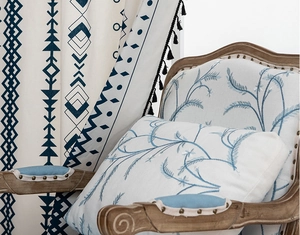Detail of bohemian geometric curtains with black fringe and matching embroidered cushions