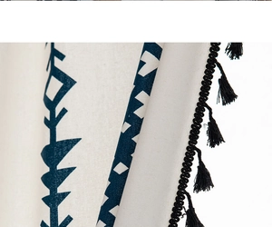 Close-up of bohemian linen curtain with navy geometric patterns and black fringe tassels