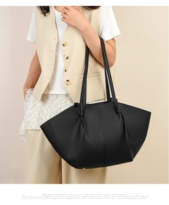Close-up of black lychee grain leather tote bag with unique knot detail on shoulder strap