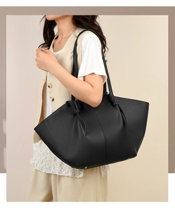 Detailed view of black litchi grain tote bag with side drawstring on female model