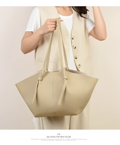 Close-up of beige winged tote bag featuring lychee grain leather and knotted shoulder strap