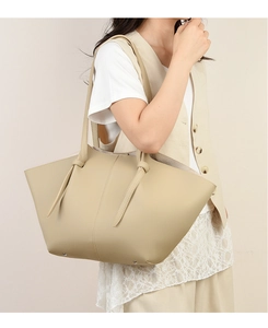 Detailed macro view of beige pebble leather tote bag with elegant metallic feet and sleek straps