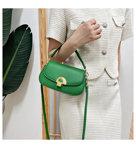 Sacoche vintage verte avec boucle dorée portée sur un ensemble de style blanc chic