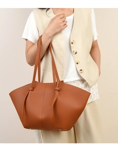 Detail of caramel tote bag showing lychee grain leather texture and metallic bottom rivets