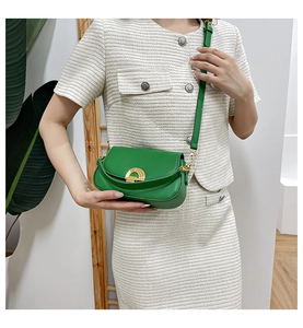 Détail du sac de selle vintage vert avec boucle dorée porté par un mannequin élégant