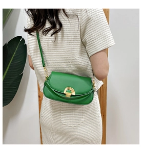 Détail du sac selle vert avec boucle métallique dorée en forme de croissant au dos