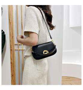 Détail du sac de selle en cuir noir minimaliste avec fermoir en métal doré brillant
