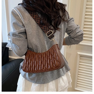 Sac hobo plissé marron avec une large bandoulière géométrique porté par un mannequin