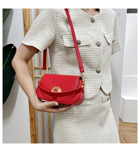Détail du sac selle rouge vintage avec boucle fer à cheval dorée et double lanière