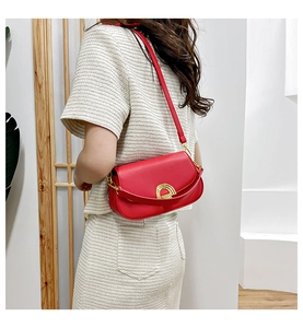 Vue détaillée du sac bandoulière rouge en cuir avec boucle dorée sur un mannequin