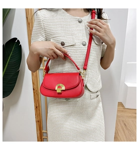Détail du sac rouge en cuir avec boucle dorée en demi-lune et finition lisse