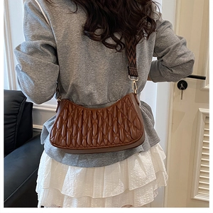 Détail d'un sac hobo plissé marron foncé avec une large bandoulière brodée