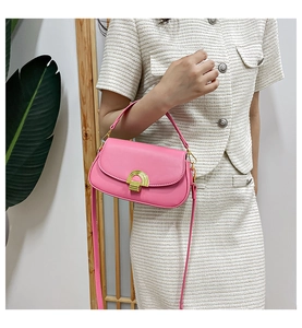 Gros plan d'un sac besace en cuir rose avec boucle dorée sur tenue en tweed blanc