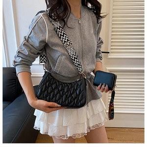 Détail d'un sac à bandoulière plissé noir avec sangle large et petit porte-monnaie
