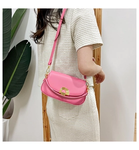 Sacoche rose avec boucle fer à cheval dorée portée à l'épaule dans un cadre moderne