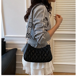 Détail du sac hobo noir matelassé avec une large bandoulière à motifs géométriques