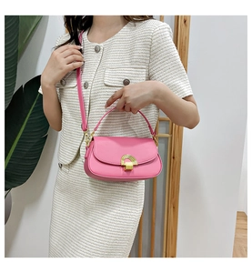 Sacoche rose avec boucle dorée portée par un mannequin en tenue blanche élégante