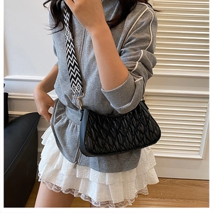 Détail du sac matelassé noir avec une large bandoulière géométrique noire et blanche chic