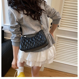 Détail du sac hobo noir matelassé avec bandoulière géométrique et boucles dorées