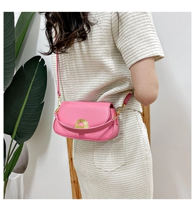 Mannequin portant un sac à bandoulière en cuir rose avec fermoir doré sur un costume beige