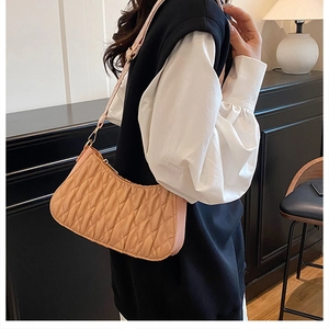Détail du sac à bandoulière plissé avec texture matelassée et zip doré sur tissu abricot clair
