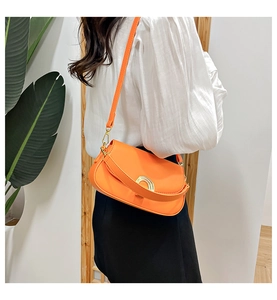 Détail d'un sac bandoulière orange en similicuir avec boucle dorée sur un mannequin