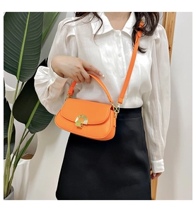 Détail du sac selle vintage orange avec boucle en métal doré et texture en cuir