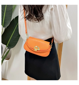 Vue de mannequin montrant le mini sac selle orange en cuir PU et son fermoir doré