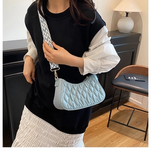 Détail du sac hobo matelassé bleu clair avec large bandoulière à motifs et fermeture éclair