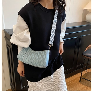 Gros plan d'un sac plissé bleu clair avec bandoulière jacquard géométrique sur mannequin