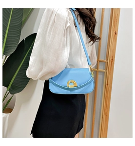 Gros plan du sac besace en cuir bleu clair avec boucle dorée en arc et fine bandoulière