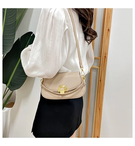 Vue détaillée du sac selle beige avec boucle dorée porté par un mannequin élégant